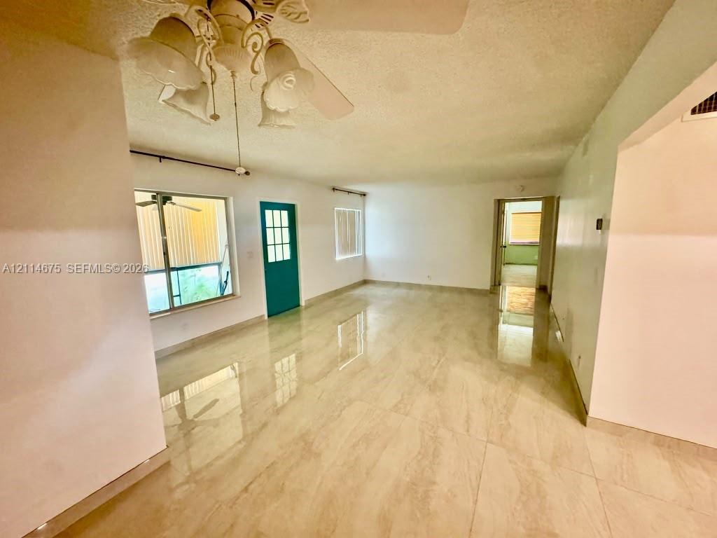 Polished stone-finish flooring, multi-pane exterior door with teal finish, dual windows with metallic frames, and decorative multi-light ceiling fixture