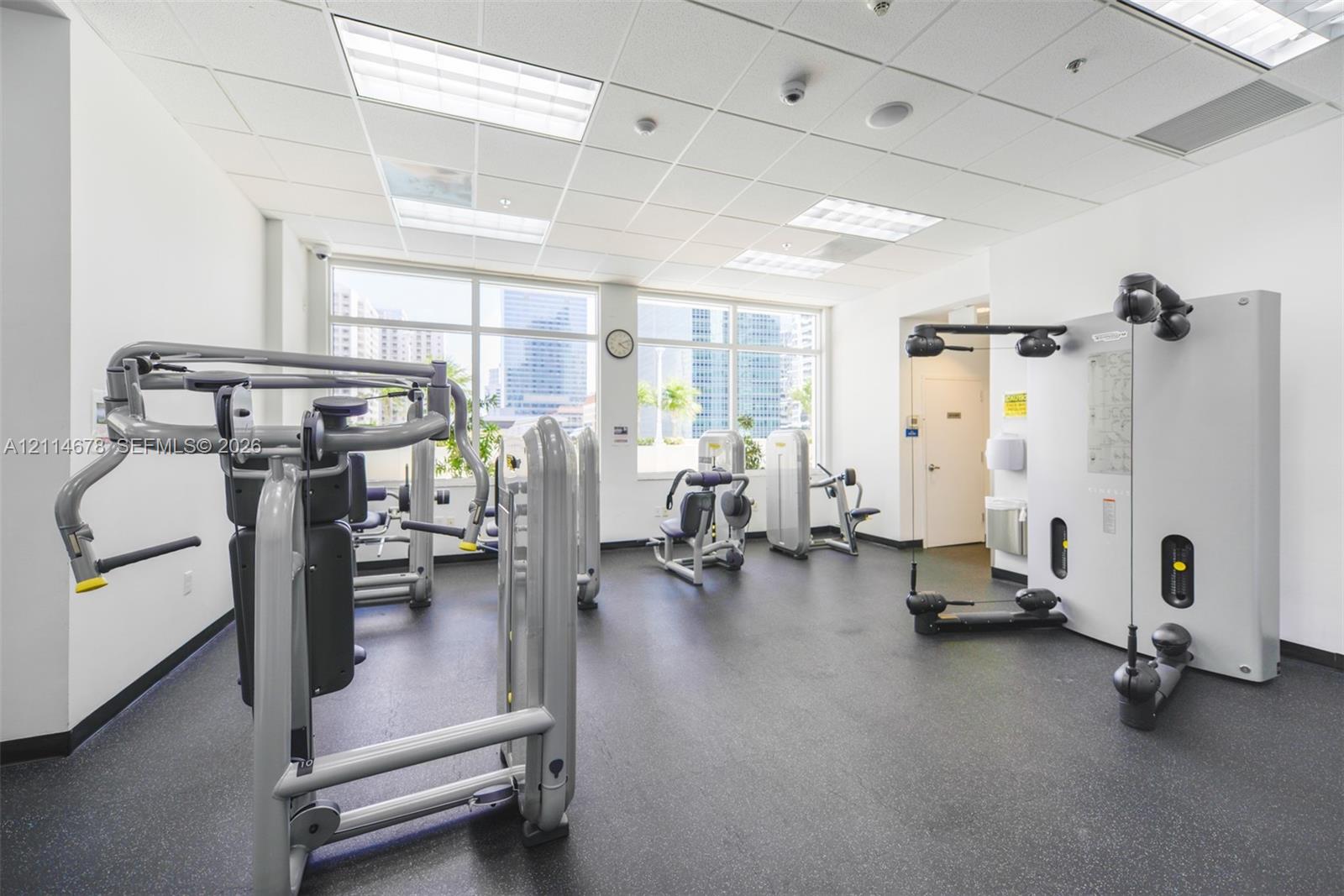 Fitness center featuring large paneled windows, recessed ceiling lighting, and rubber flooring