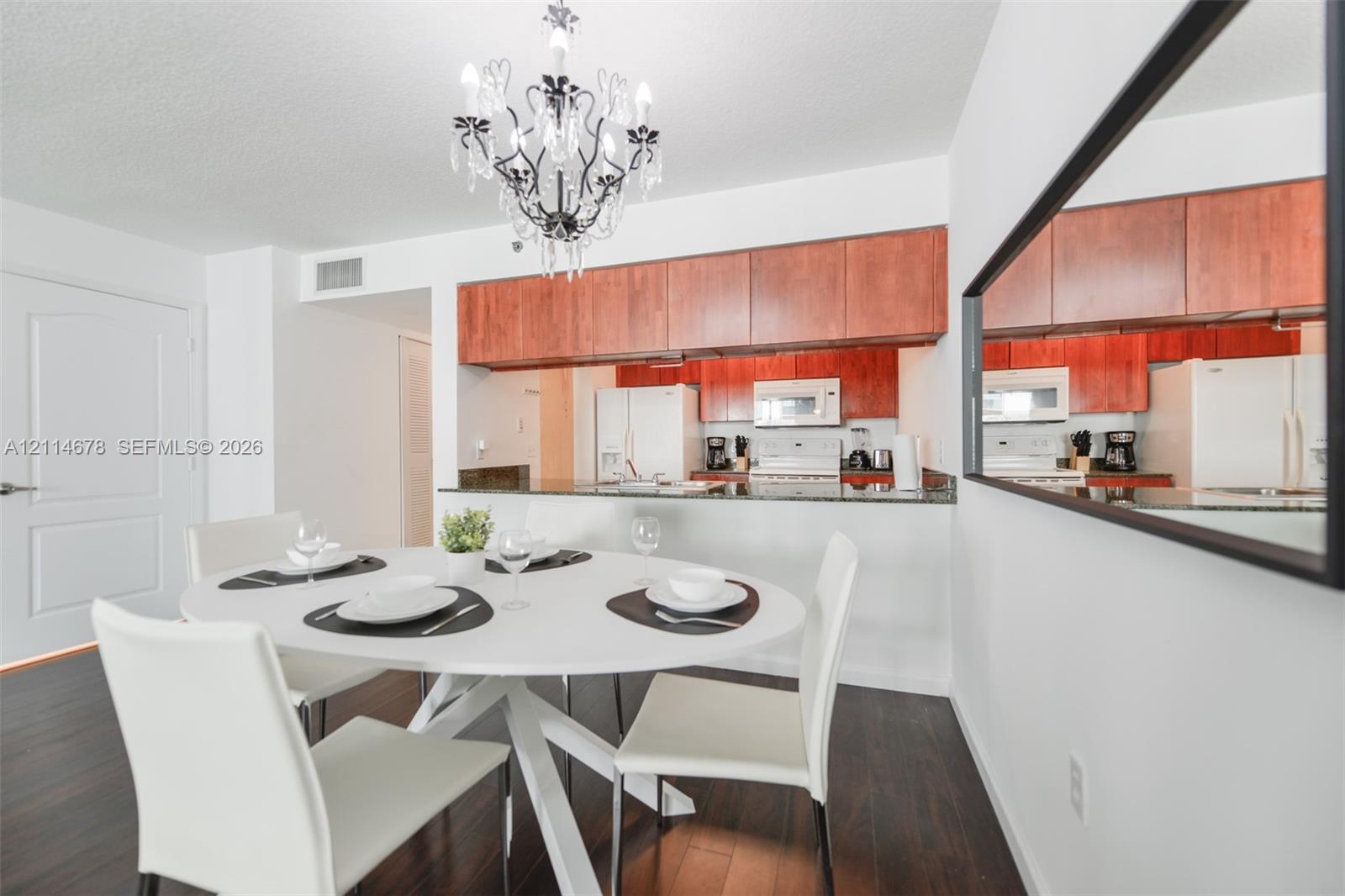 Dining area featuring wood-finish flooring, a decorative chandelier, and a large wall-mounted mirror