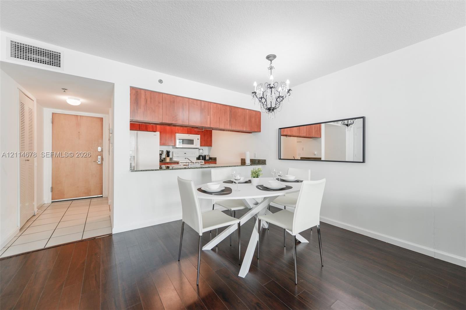 Kitchen featuring wood cabinetry, stone countertops, and built-in appliances, accented by wood-finish flooring and a decorative chandelier