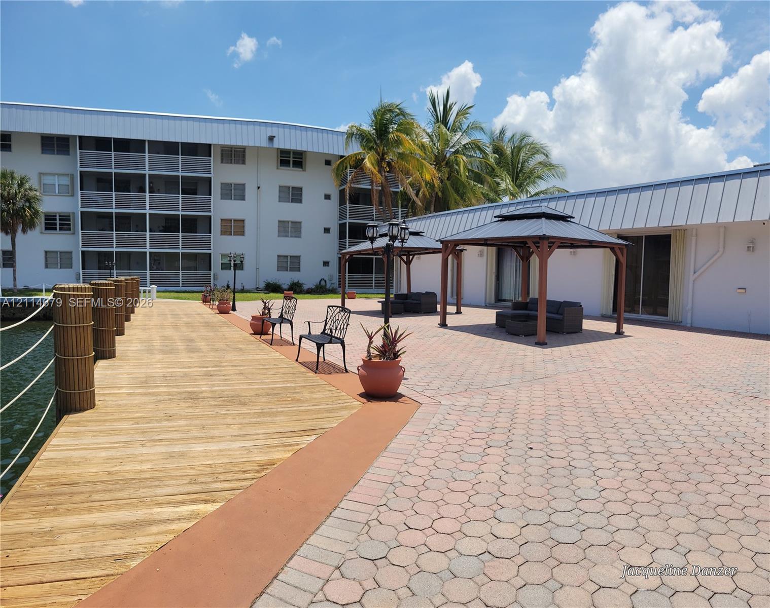 Waterfront deck with wood-finish decking, interlocking paver patio, and two permanent metal-frame gazebos