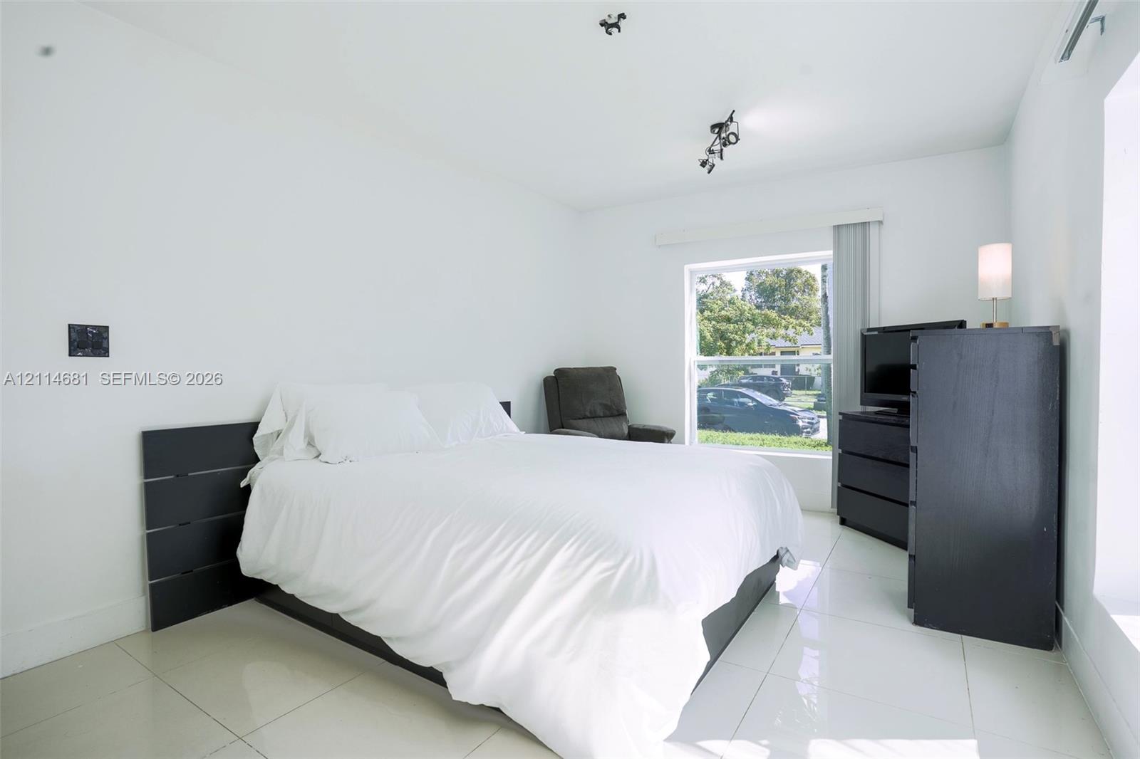 Bright, neutral room featuring large-format polished tile flooring and a multi-pane window with natural light exposure