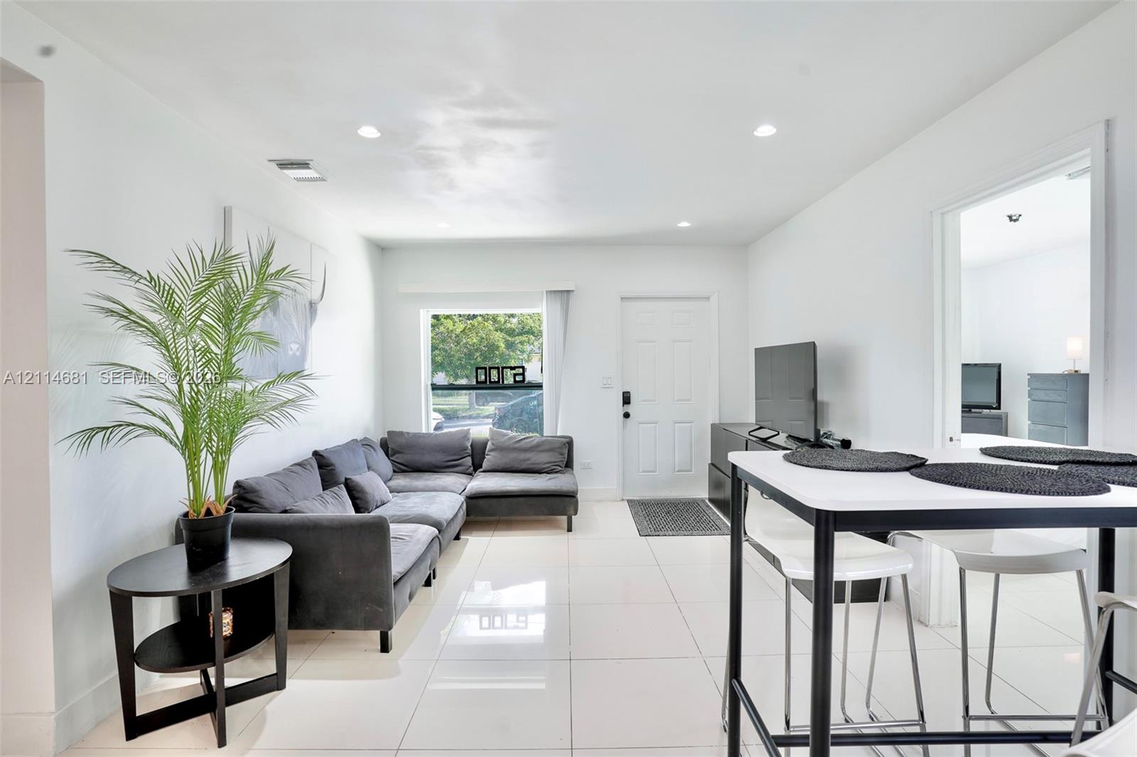 Open-concept interior featuring large-format tile flooring, recessed ceiling lighting, and natural light from a rectangular window
