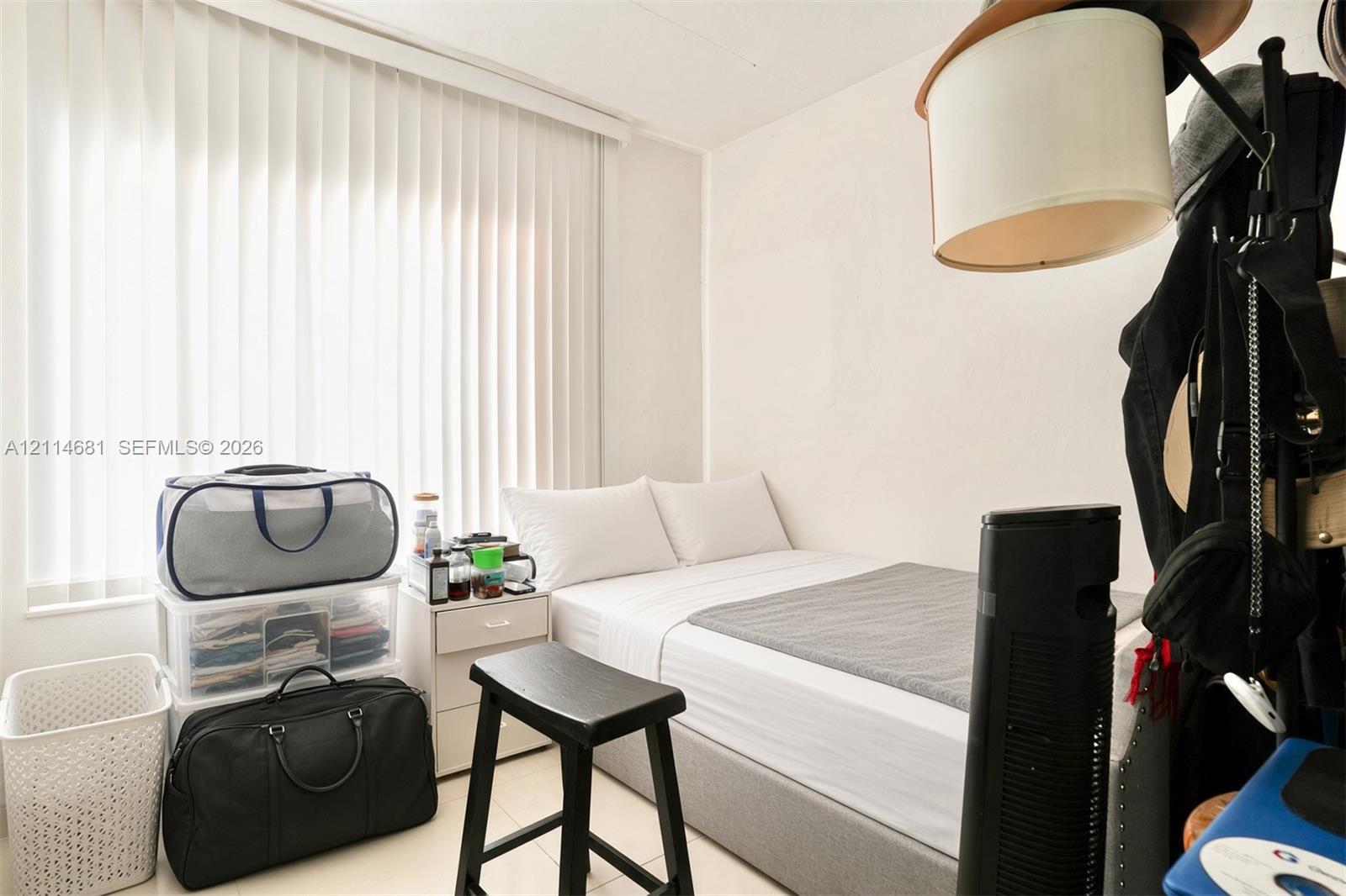 Room featuring white walls, neutral-toned tile flooring, and vertical window blinds