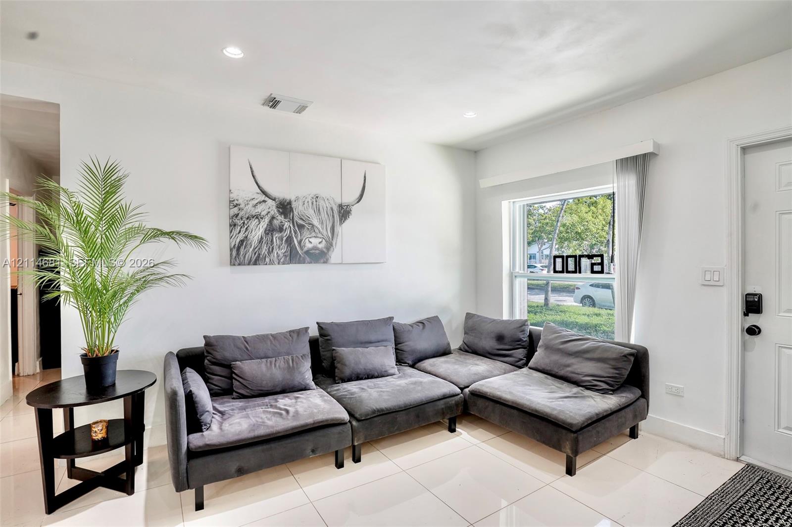 Neutral-toned interior featuring large-format ceramic tile flooring, recessed lighting, and a window providing natural light