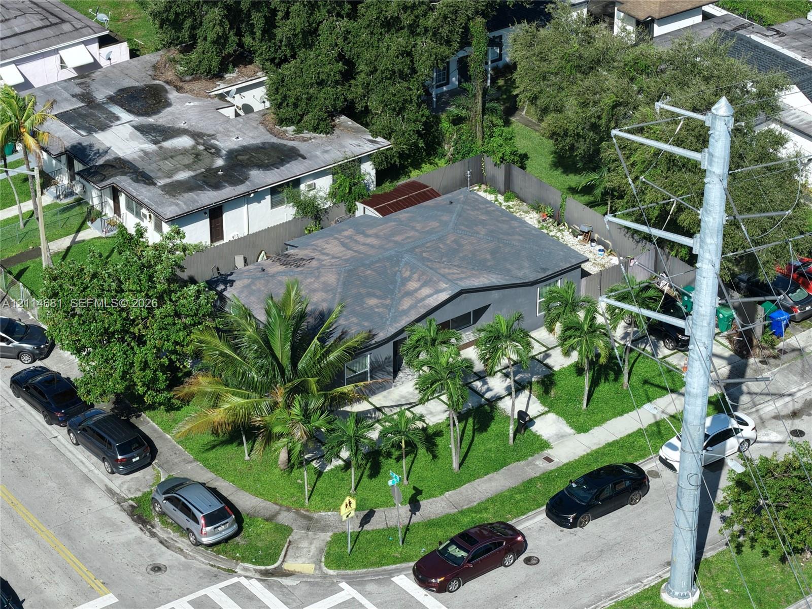 Corner lot property featuring a low-slope roof, mature palm trees, and an enclosed rear yard area