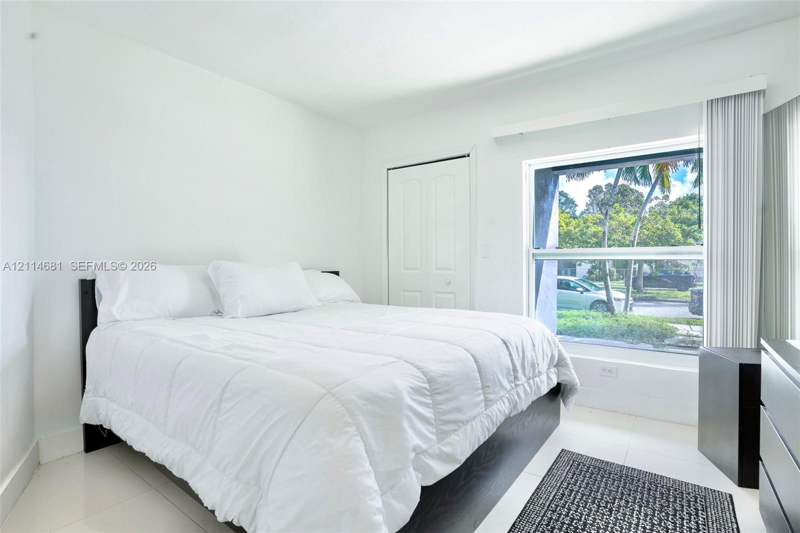 Room featuring neutral-toned ceramic tile flooring, a large horizontal window, and a built-in closet with double doors