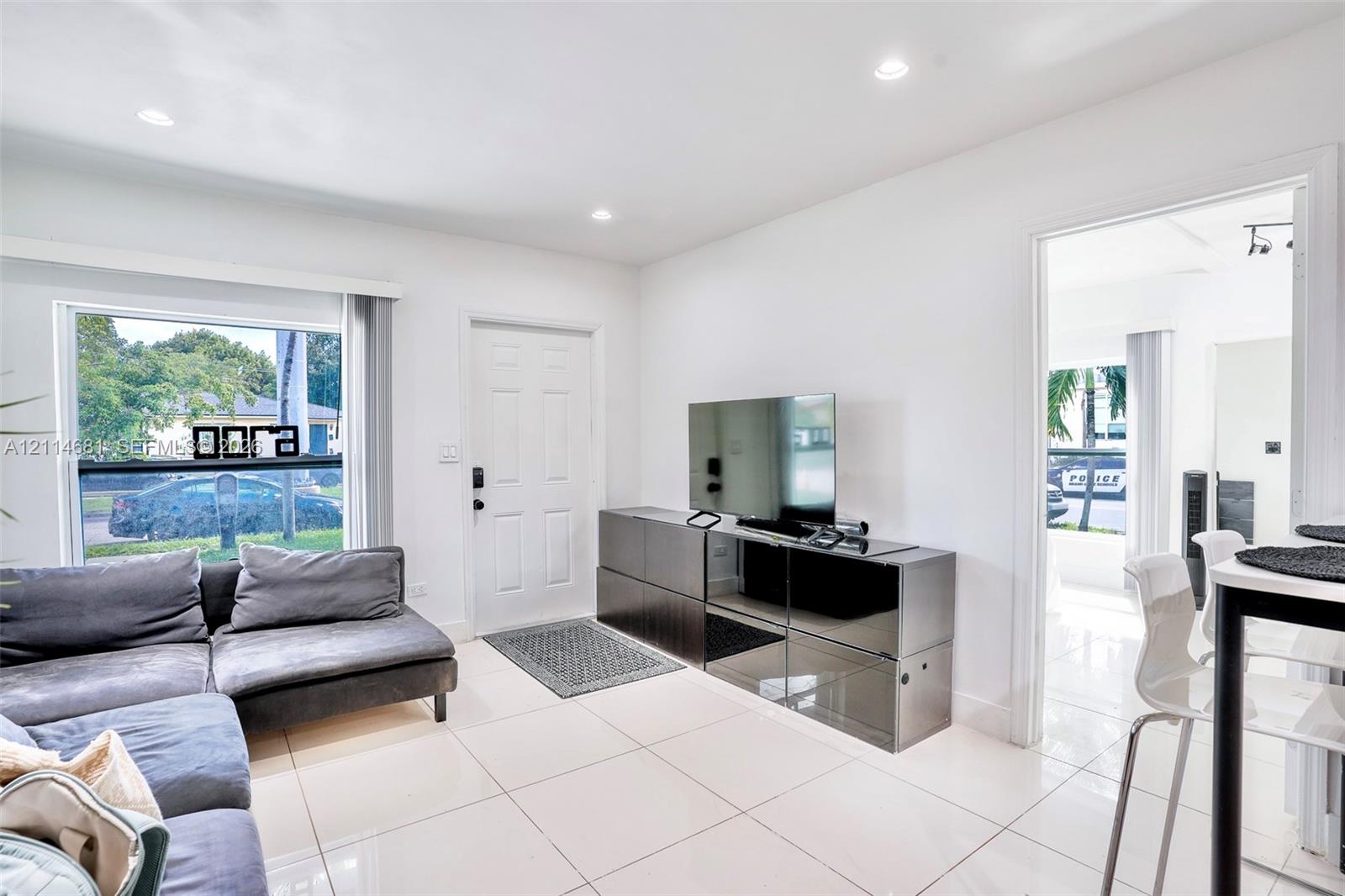 Neutral-toned tile flooring, recessed ceiling lighting, and large window with natural light