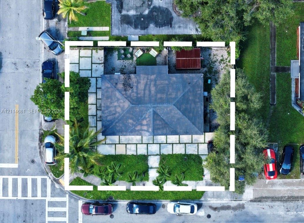 Aerial perspective featuring a hip roof, large-format concrete paver hardscaping, mature landscaping, and peripheral fencing