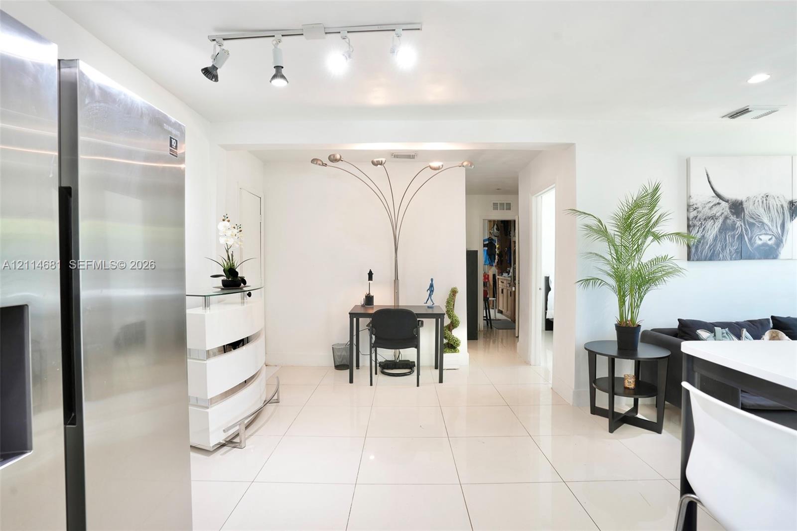 Interior space featuring large-format ceramic tile flooring, stainless steel refrigerator, and adjustable multi-directional track lighting