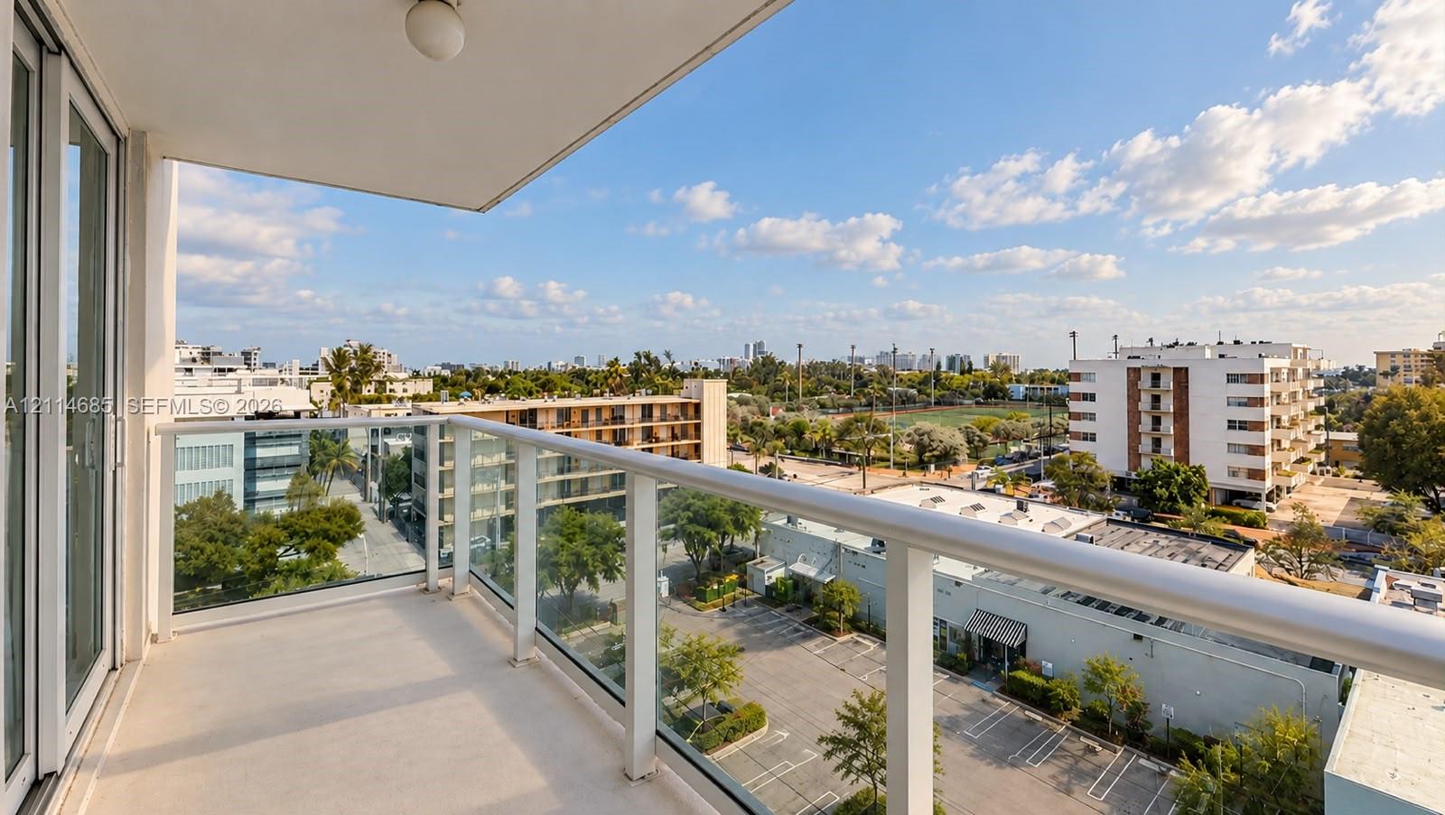 Private balcony featuring a glass panel railing and solid surface flooring