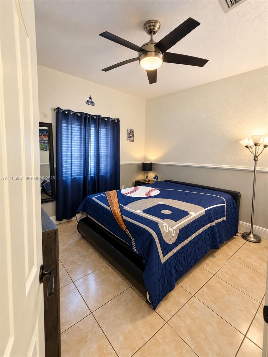 Neutral-toned tile flooring, chair rail molding, and a brushed nickel ceiling fan with integrated lighting