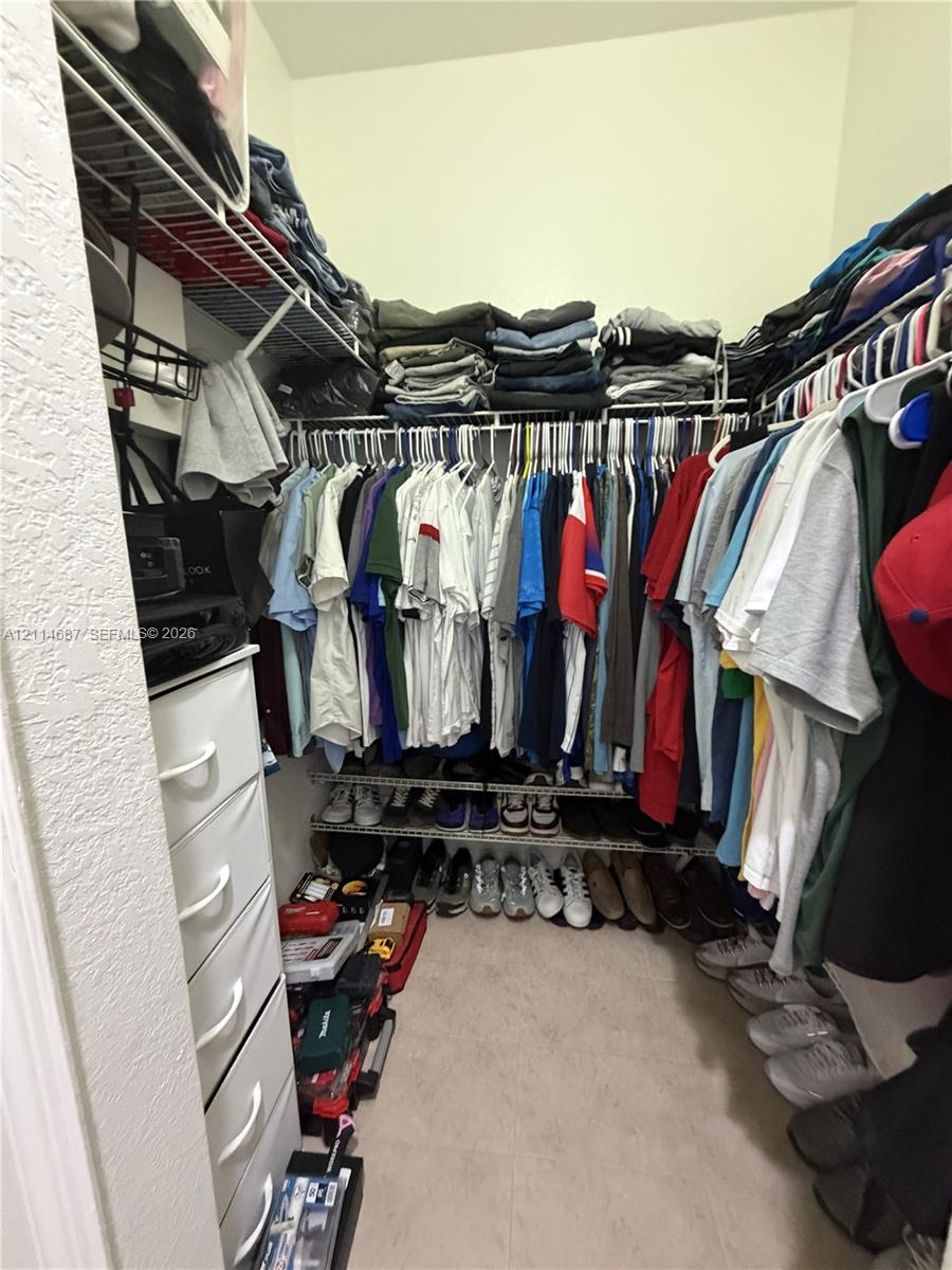 Walk-in storage space featuring tiered wire shelving, built-in vertical drawer cabinetry, and surface-level floor storage