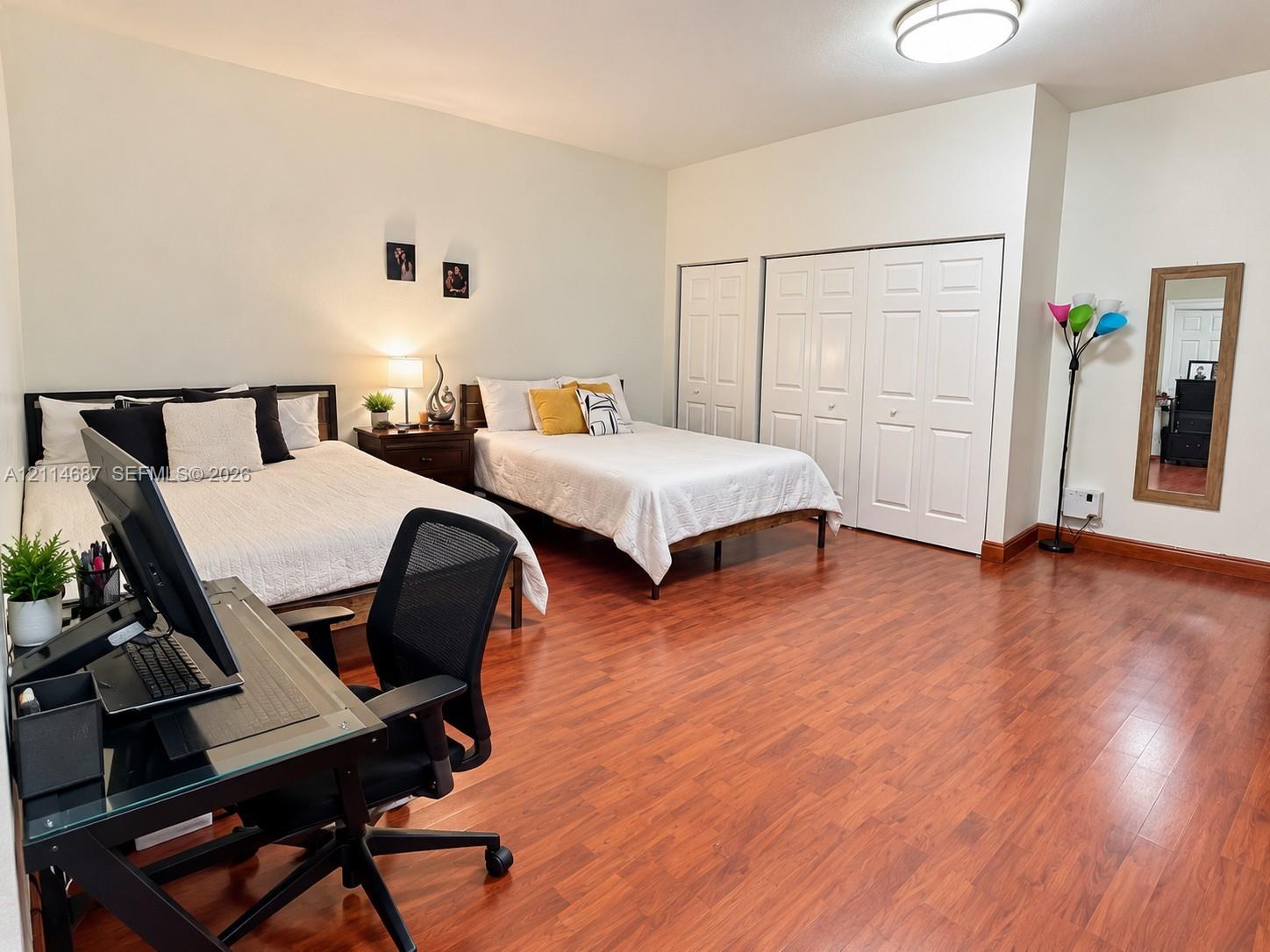 Spacious room featuring wood-finish flooring, recessed ceiling lighting, and double-door closet storage