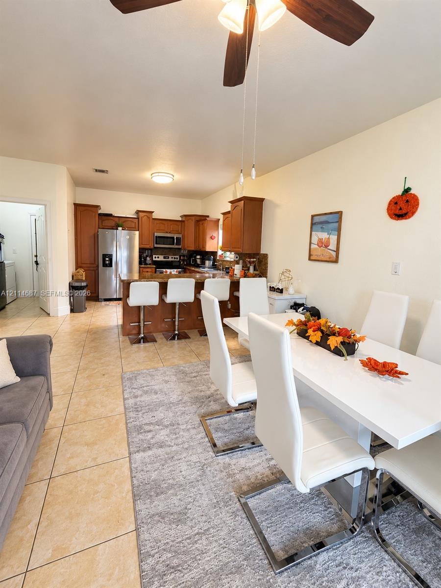 Kitchen featuring wood cabinetry, a breakfast bar, stainless steel appliances, and tile flooring Kitchen featuring wood cabinetry, a breakfast bar, stainless steel appliances, and tile flooring