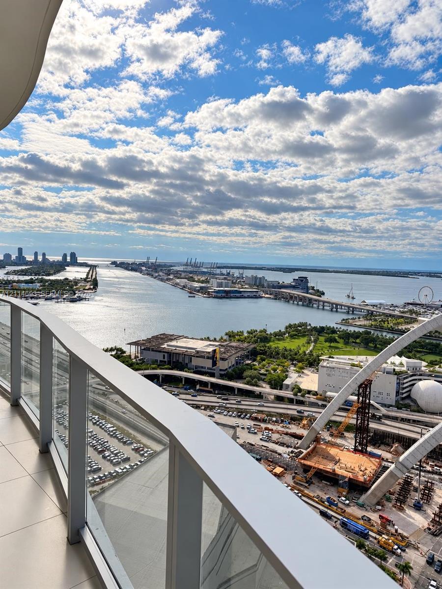 Private balcony featuring glass panel railing and tile flooring, offering a wide-angle perspective of the harbor, bridges, and surrounding cityscape