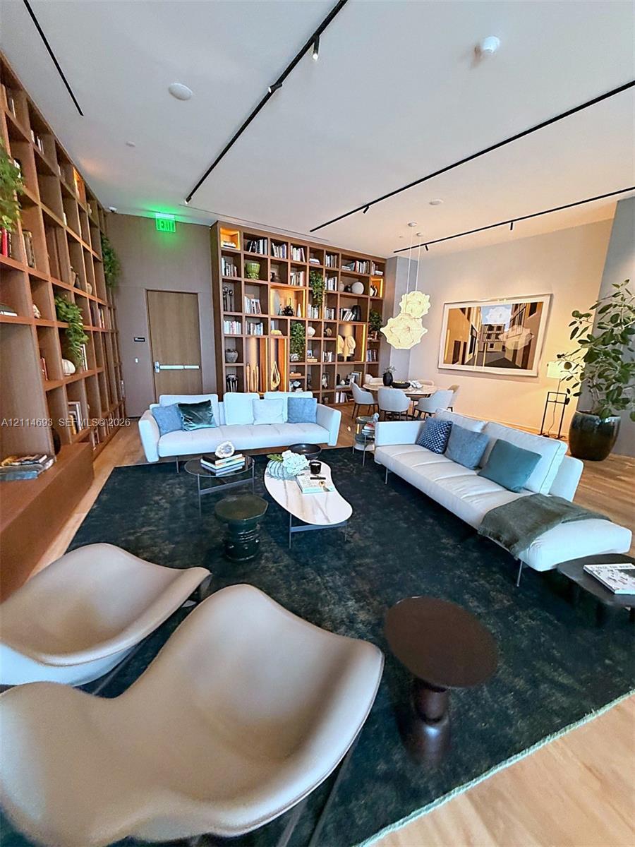 Floor-to-ceiling built-in wood shelving, track lighting, and wood-finish flooring
