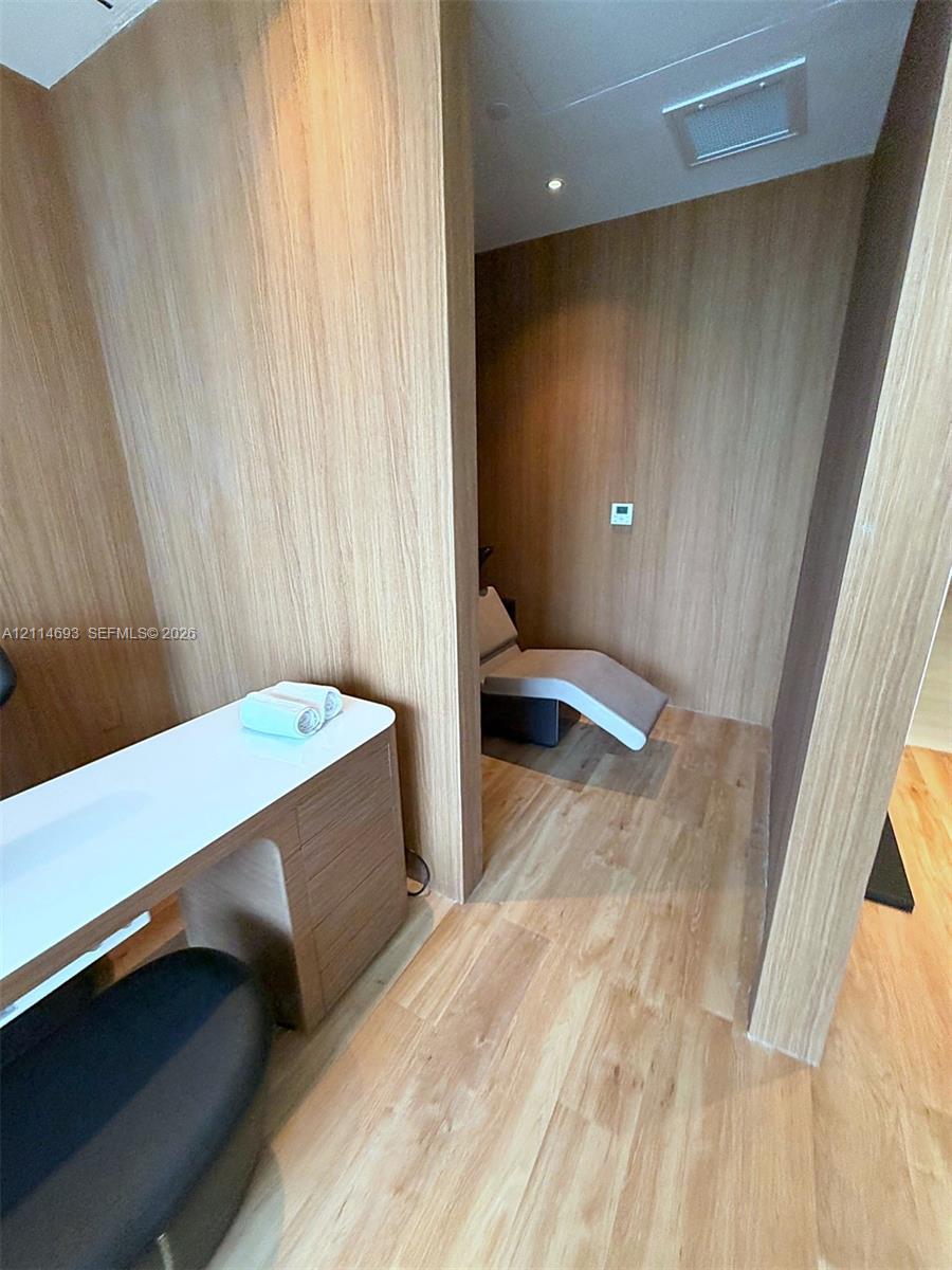 Custom built-in wood-finish cabinetry, integrated desk surface with white countertop, and consistent wood-finish wall paneling and flooring throughout
