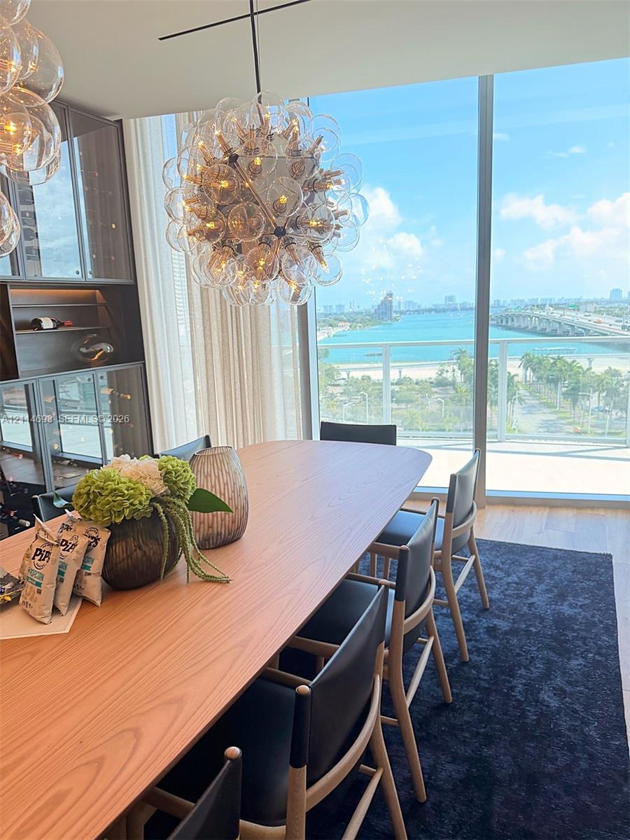 Floor-to-ceiling glass windows, custom built-in cabinetry, spherical multi-bulb chandelier, and wood-finish flooring