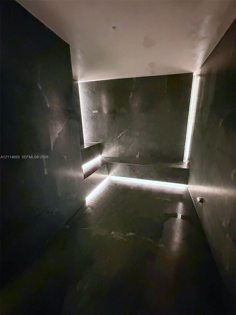 Dark-toned natural stone wall and floor cladding featuring integrated LED cove lighting and built-in stone seating