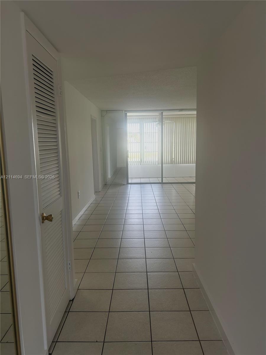 Interior area featuring square tile flooring, louvered closet door, and glass sliding doors Interior area featuring square tile flooring, louvered closet door, and glass sliding doors