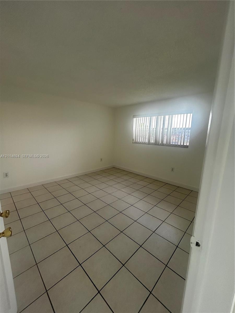 Neutral-toned interior space featuring ceramic tile flooring and vertical window blinds