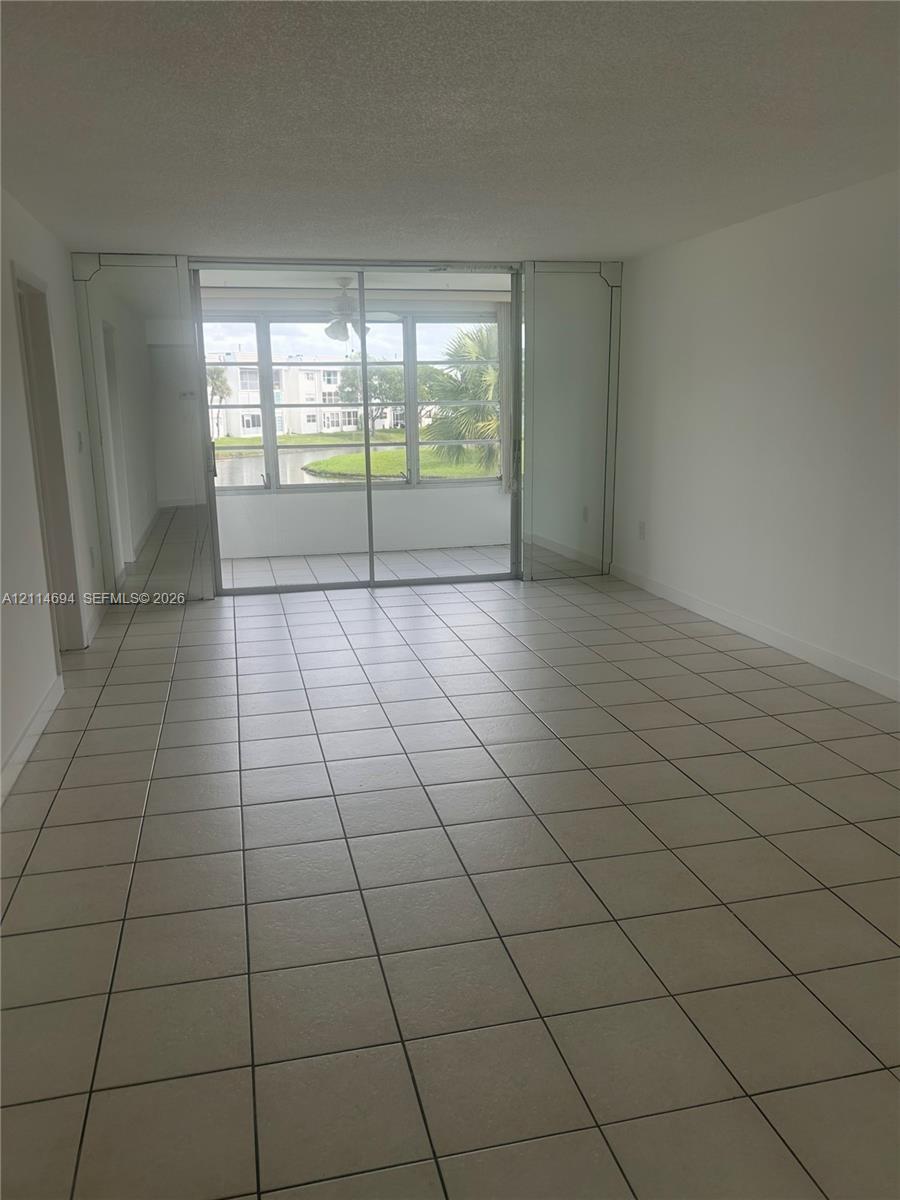 Ceramic tile flooring, mirrored wall accents, and sliding glass doors with exterior access to an enclosed balcony