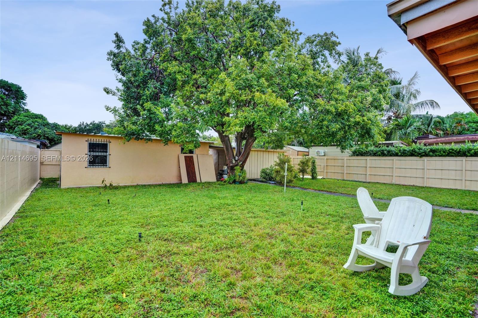Backyard featuring a grass lawn, mature tree, and perimeter privacy fencing