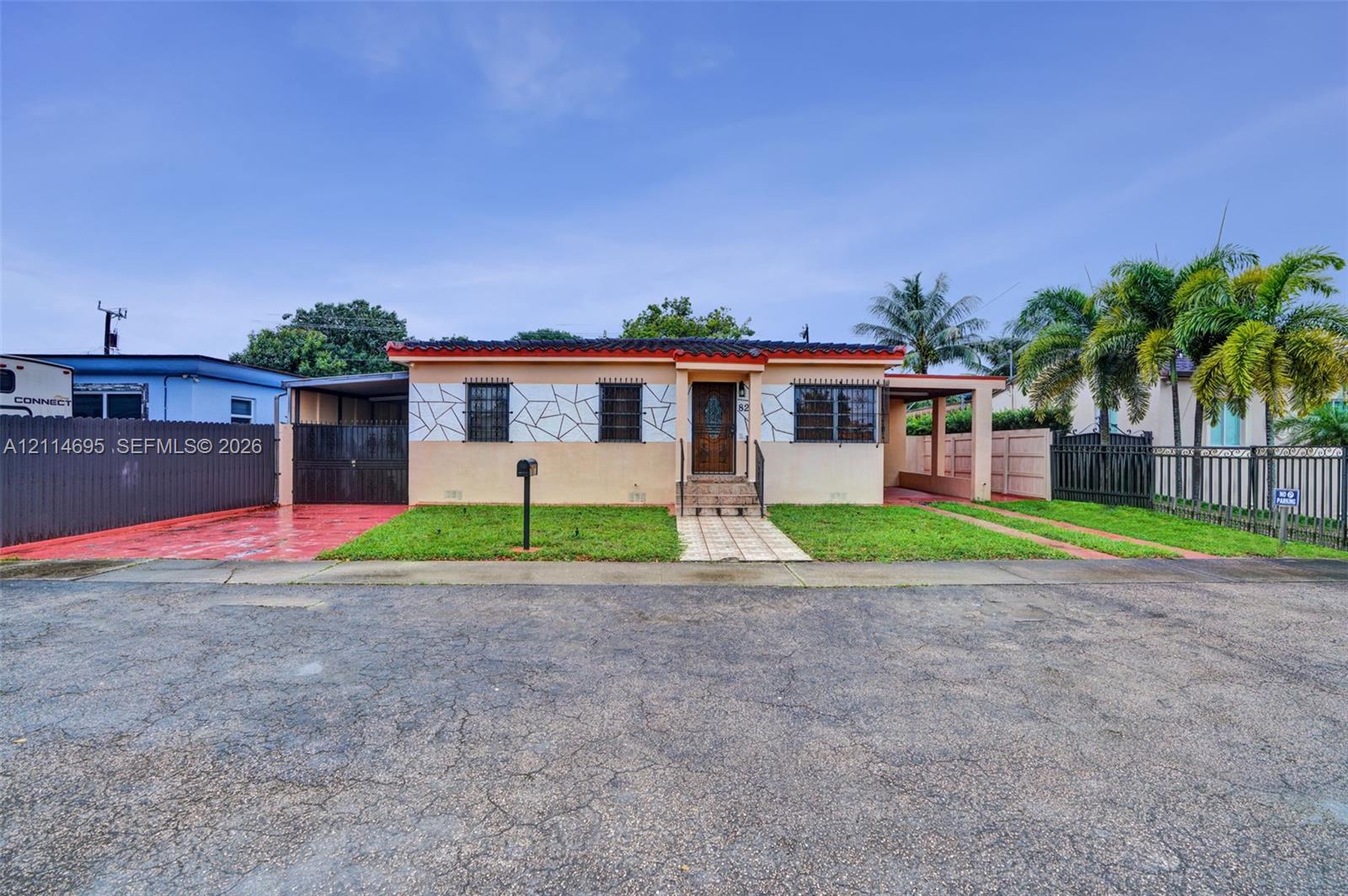 Single-story exterior featuring decorative stone accents, dual carport parking, gated fencing, and a front entryway with tile steps