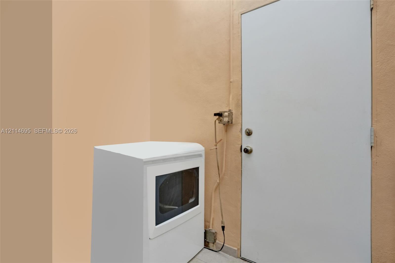 Utility area featuring a white appliance with a glass door panel and a solid white swing door