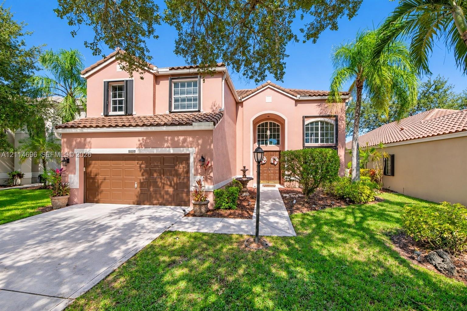 Two-story stucco exterior featuring a tile roof, arched entryway, multi-paned windows, and a concrete driveway leading to an attached two-car garage Two-story stucco exterior featuring a tile roof, arched entryway, multi-paned windows, and a concrete driveway leading to an attached two-car garage