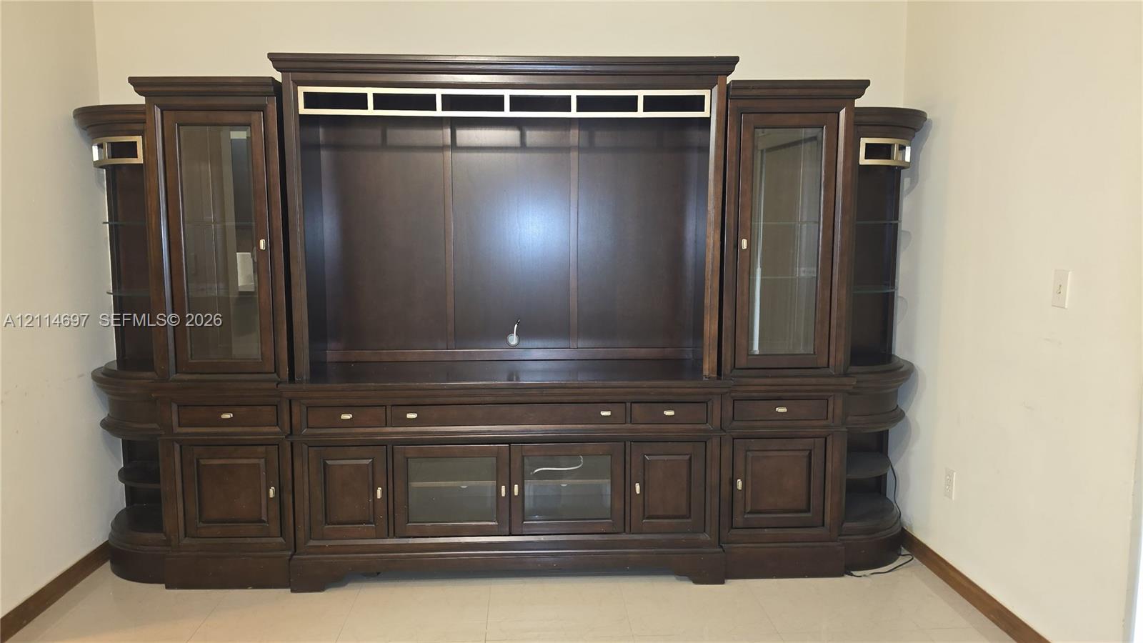 Built-in wall unit featuring dark-stained wood cabinetry, glass-paneled display doors, integrated shelving, and multi-drawer storage