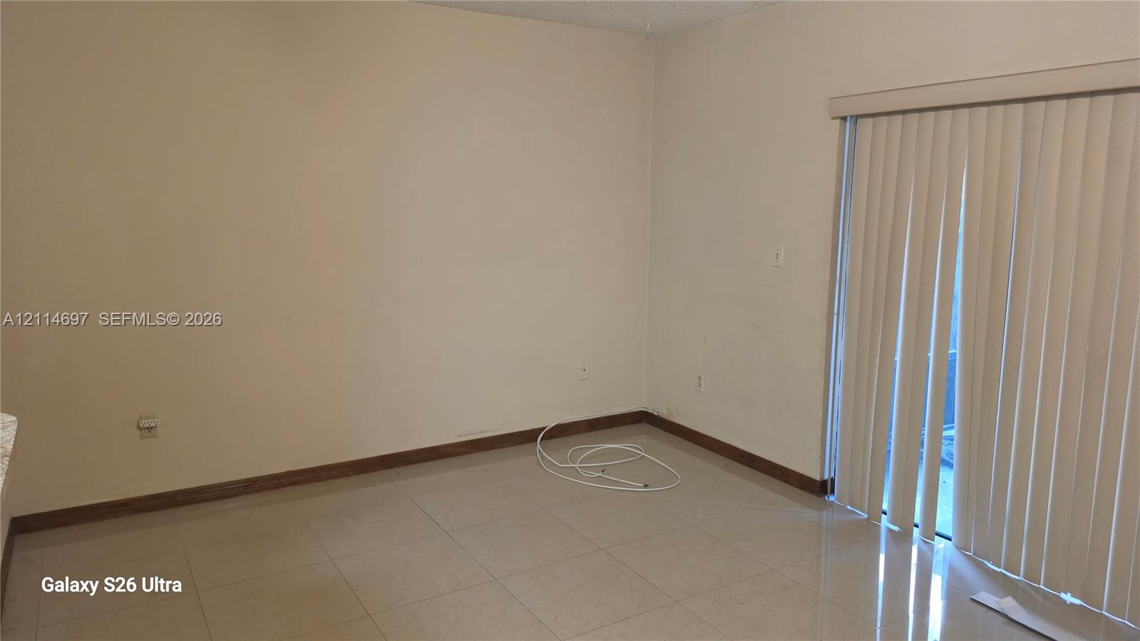 Neutral-toned wall finish, large-format tile flooring, and vertical sliding glass door with integrated blinds