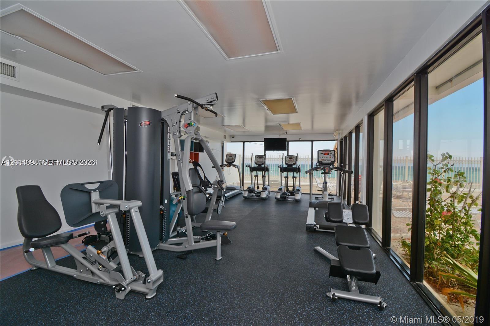 Fitness center with rubberized flooring, recessed lighting, and floor-to-ceiling windows