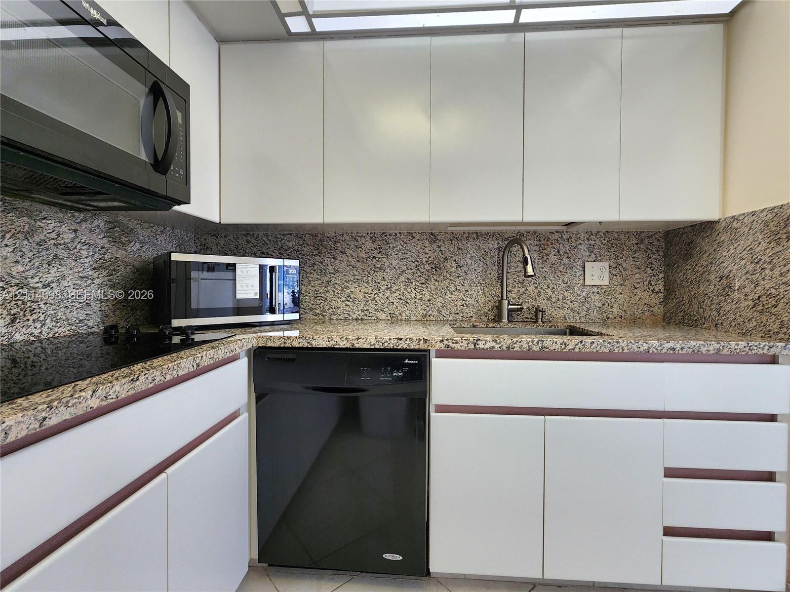 Kitchen featuring flat-panel cabinetry, stone countertops, integrated stone backsplash, stainless steel sink
