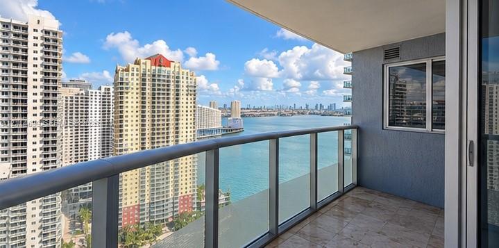 Covered balcony featuring tile flooring and a glass-paneled metal railing