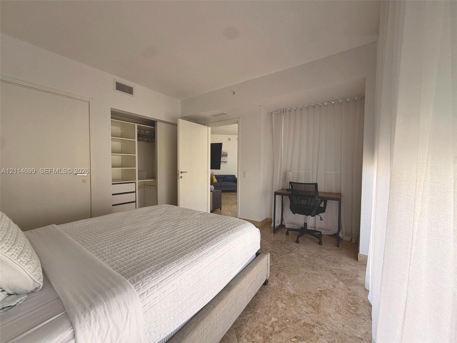 Stone flooring, custom built-in closet organization system with shelving and drawers, and floor-to-ceiling drapery