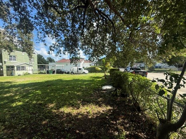 Expansive grounds featuring mature shade trees, established perimeter shrubbery, and a chain-link fence