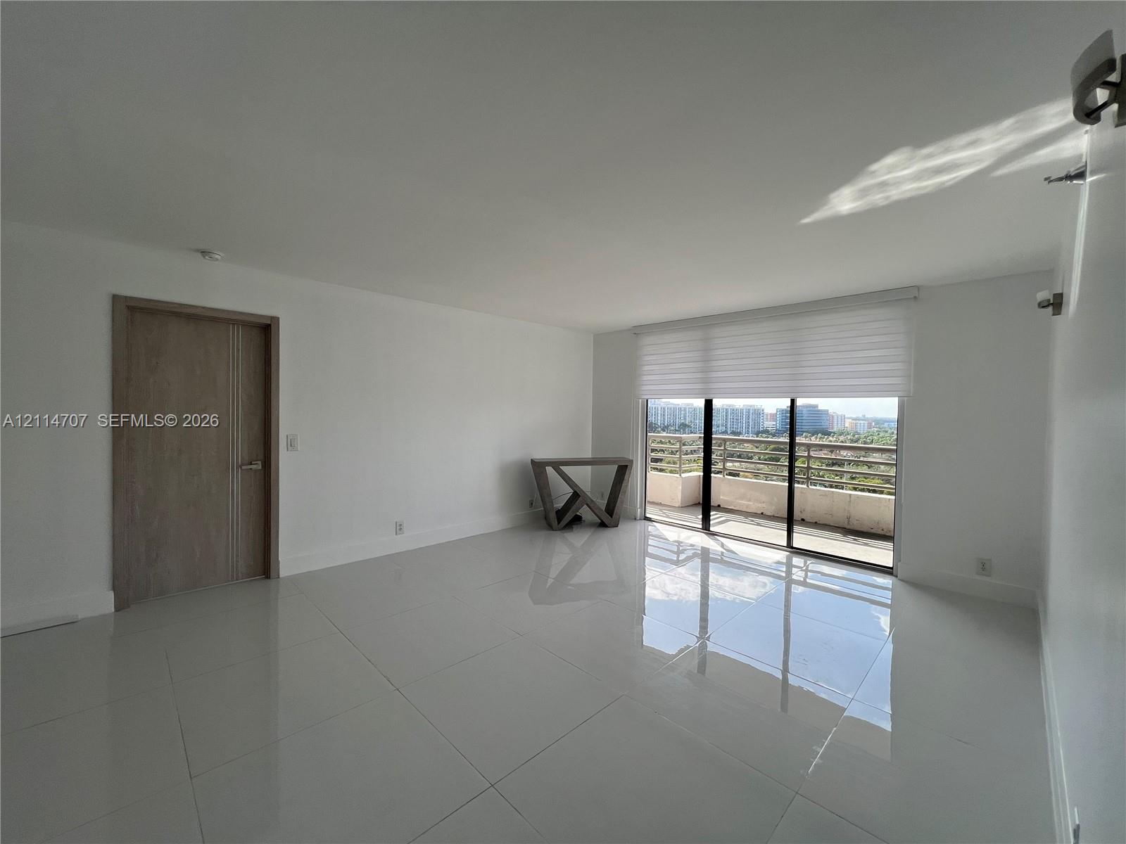 Interior space featuring polished stone-finish flooring, floor-to-ceiling sliding glass doors, motorized window shades, and a wood-finish interior door