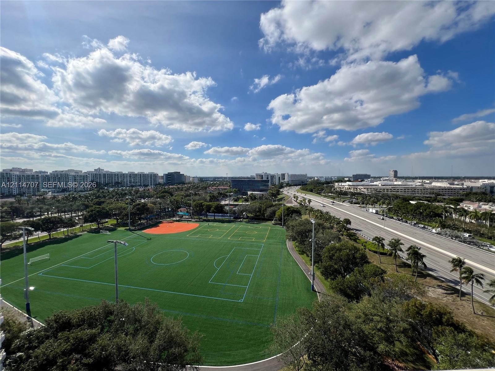Elevated aerial perspective featuring a multi-sport turf field with integrated markings, perimeter lighting, and paved walking paths