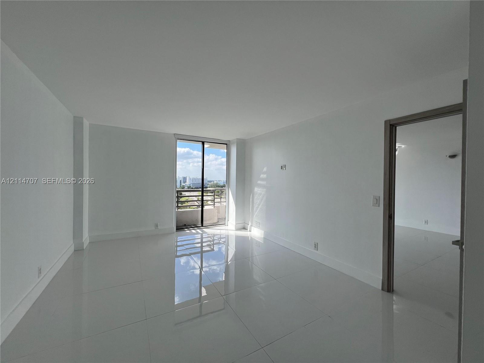 Neutral-toned interior featuring large-format tile flooring, smooth wall finishes, and a sliding glass door providing external access