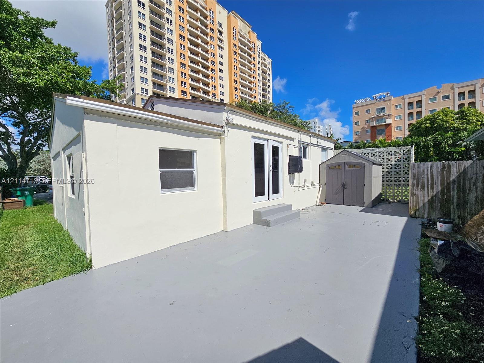 Concrete patio, exterior double doors, and detached storage structure