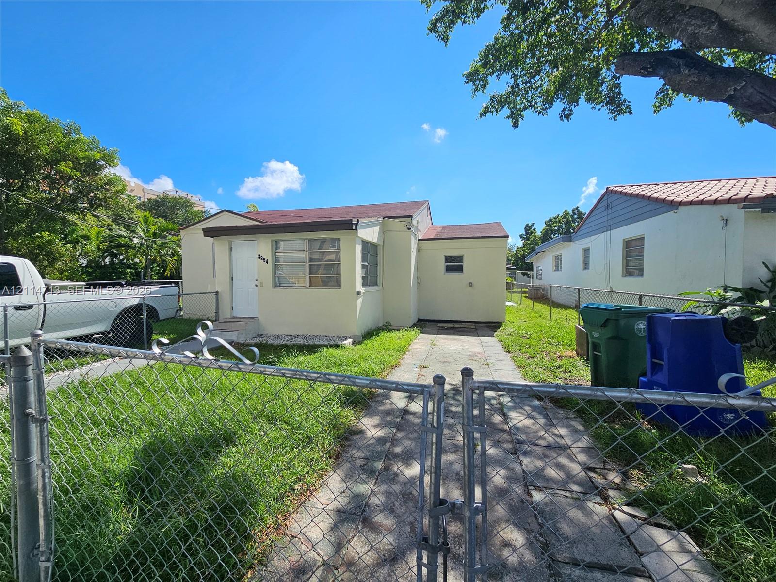 Single-story exterior featuring light-toned stucco siding, a tiled roof, and a paved driveway