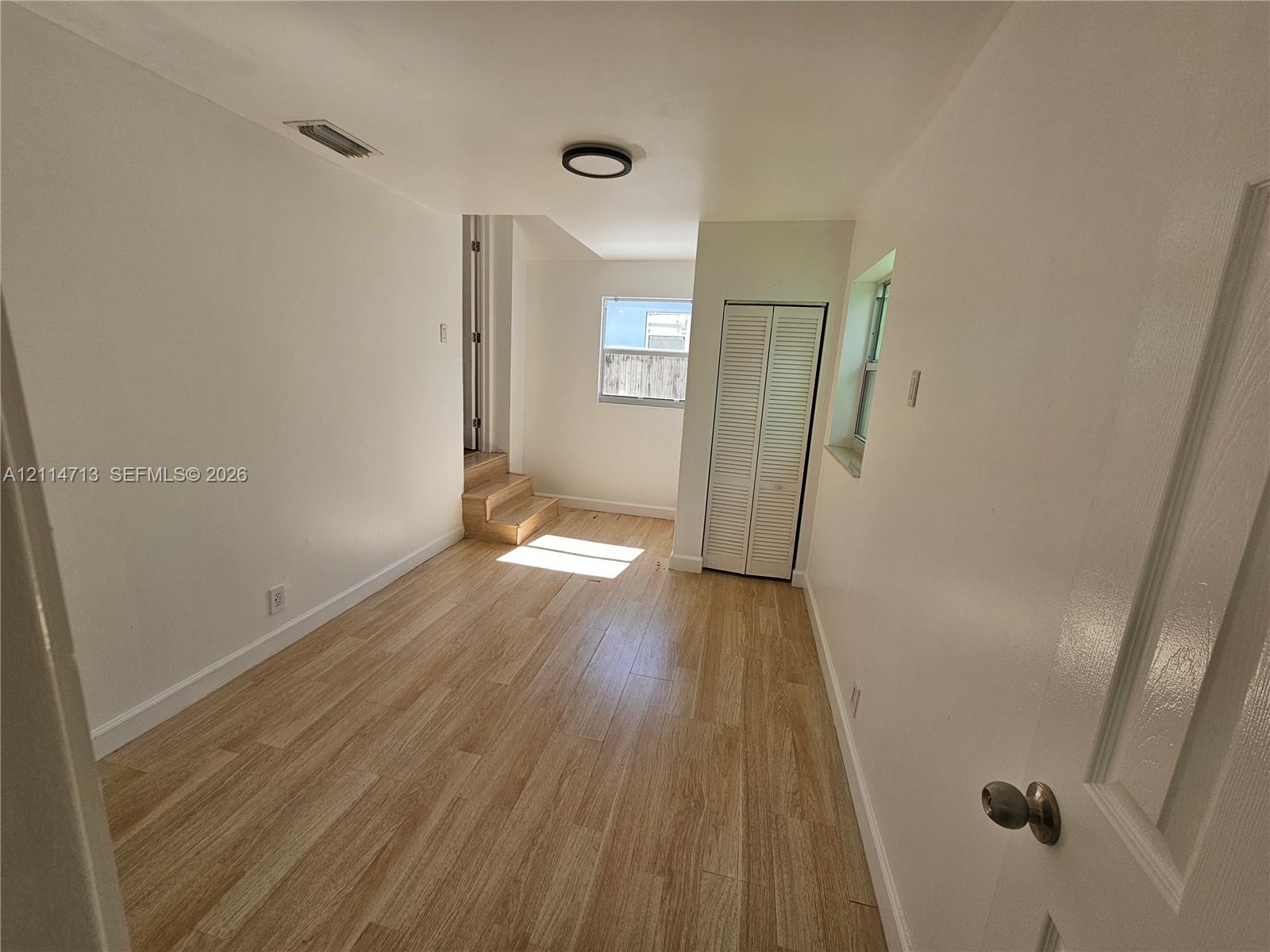 Wood-finish flooring, white walls, dual bi-fold closet doors, and recessed ceiling lighting