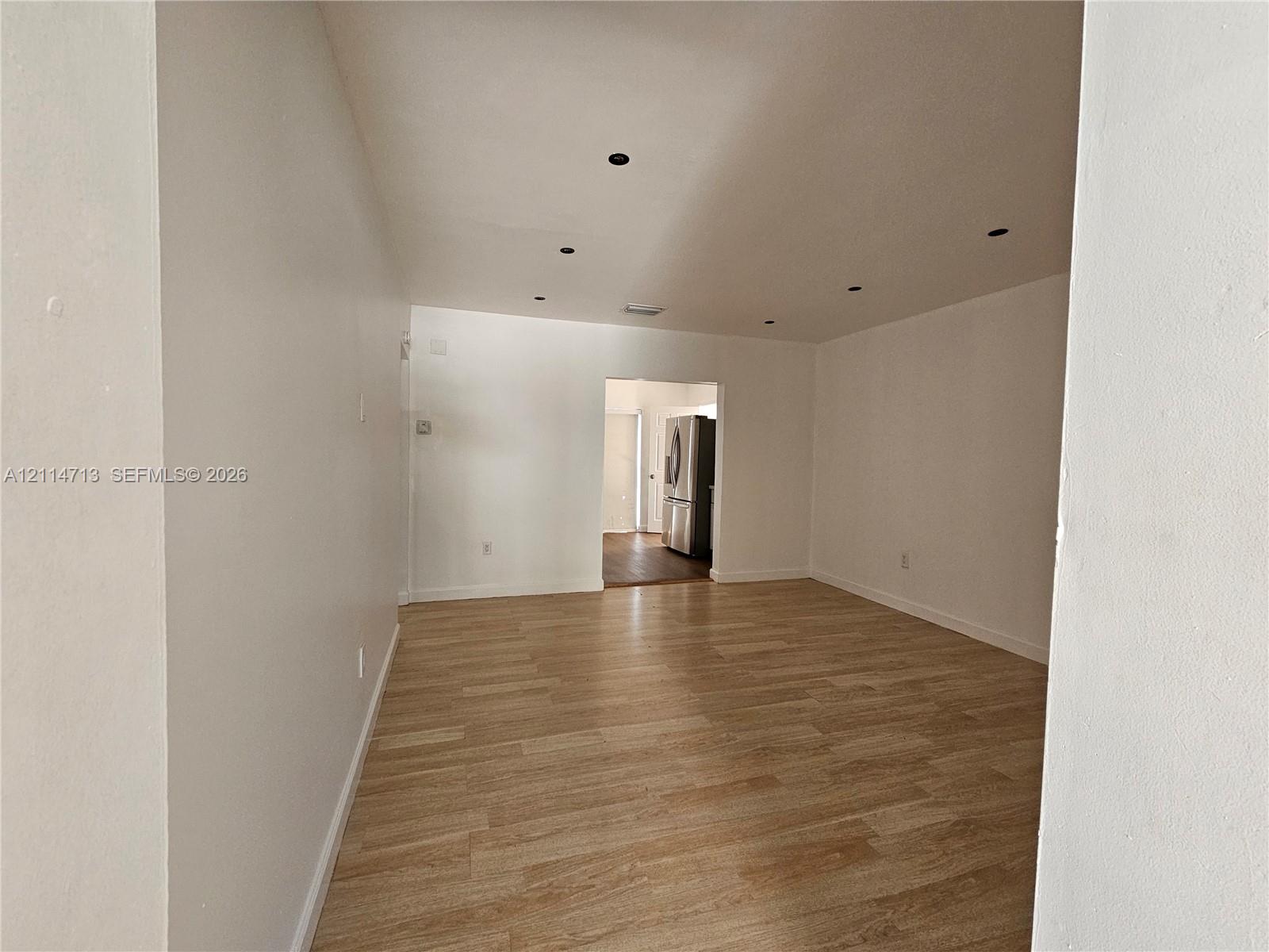 Neutral-toned interior space featuring light wood-finish flooring and recessed ceiling lighting