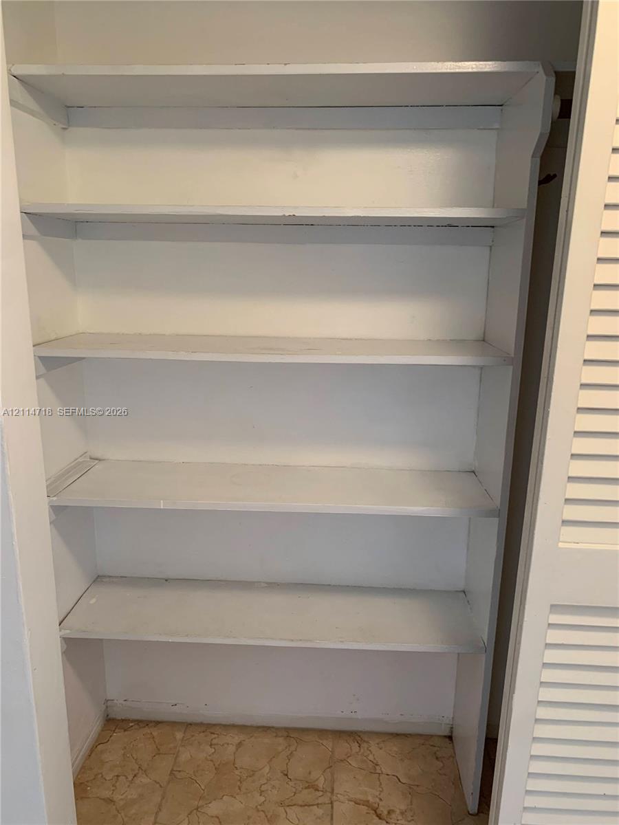 Built-in floor-to-ceiling shelving unit featuring four white-finished storage tiers and louvered closet doors