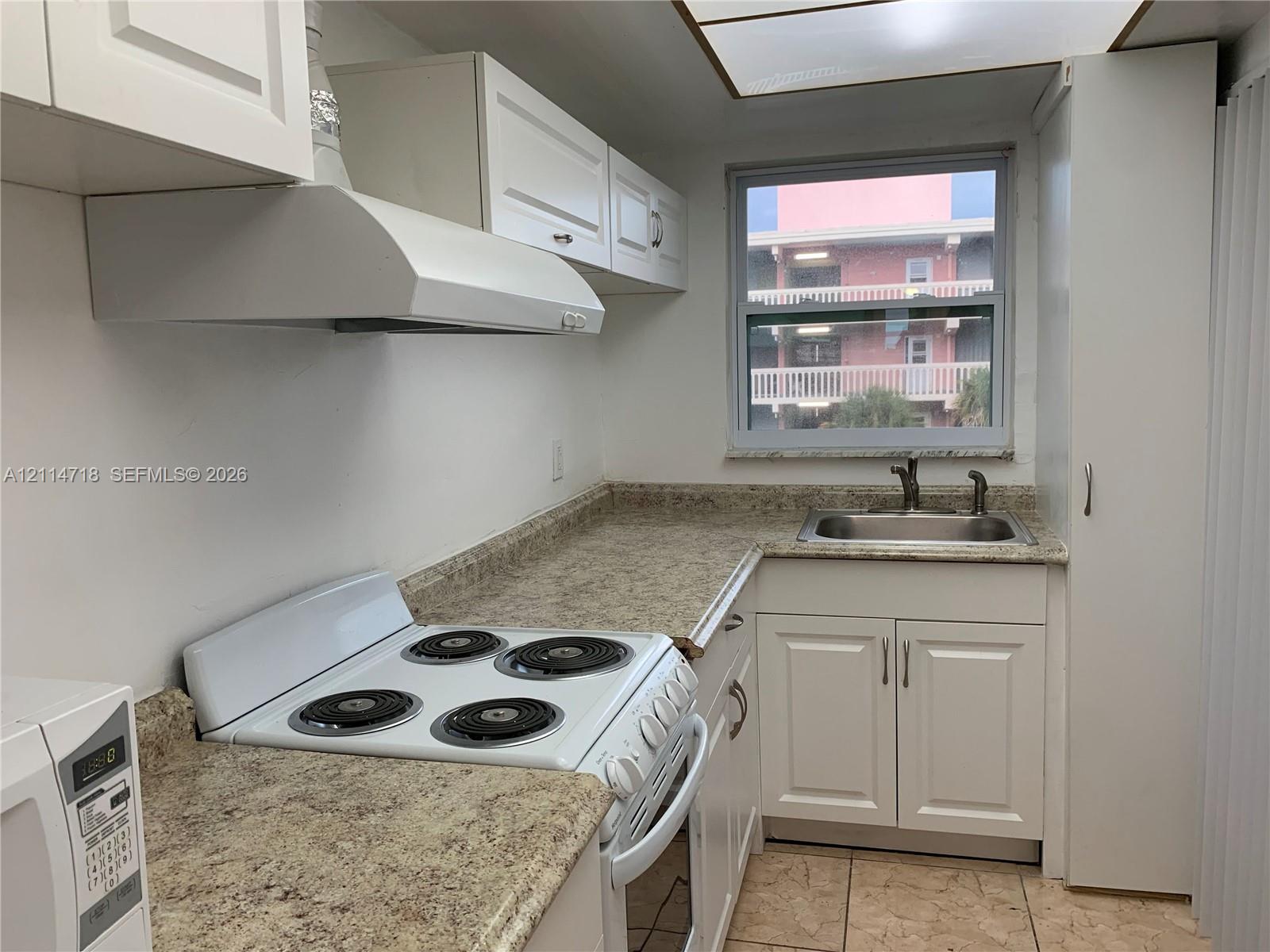 Kitchen featuring white cabinetry, stone-finish countertops, stainless steel sink with a high-arc faucet, white electric range, and tile flooring