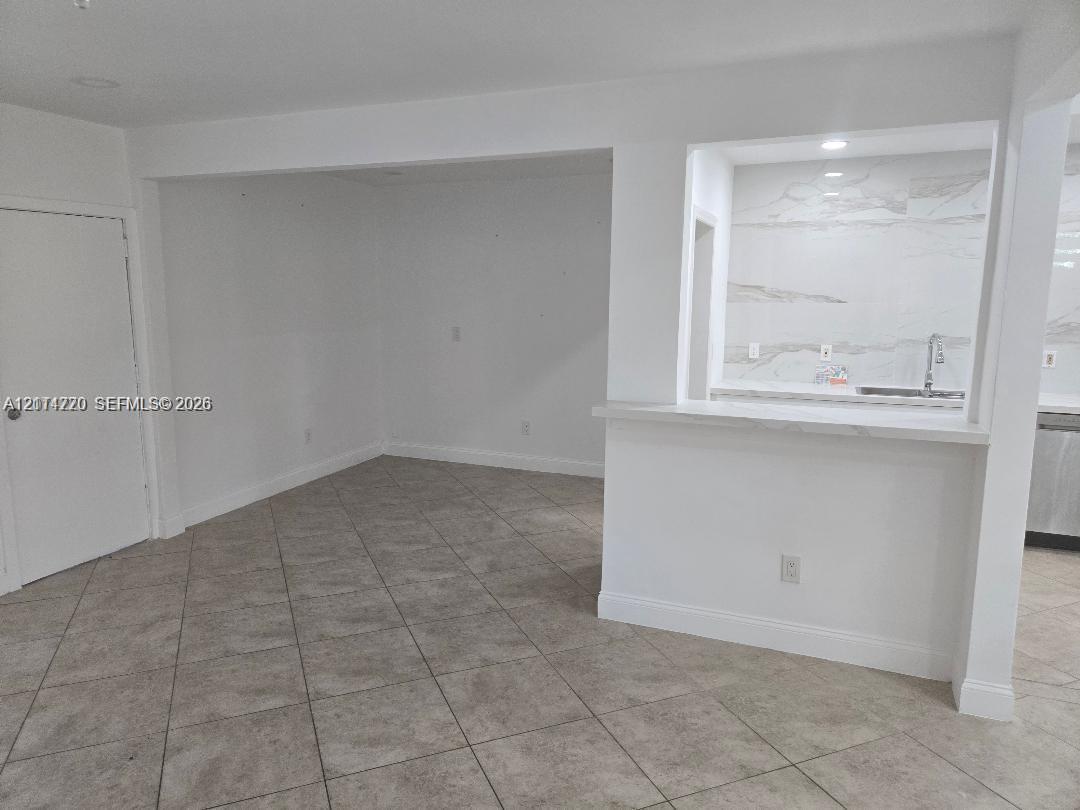 Ceramic tile flooring, pass-through breakfast bar with a stone-finish countertop, and full-height stone-finish backsplash with an undermount sink Ceramic tile flooring, pass-through breakfast bar with a stone-finish countertop, and full-height stone-finish backsplash with an undermount sink