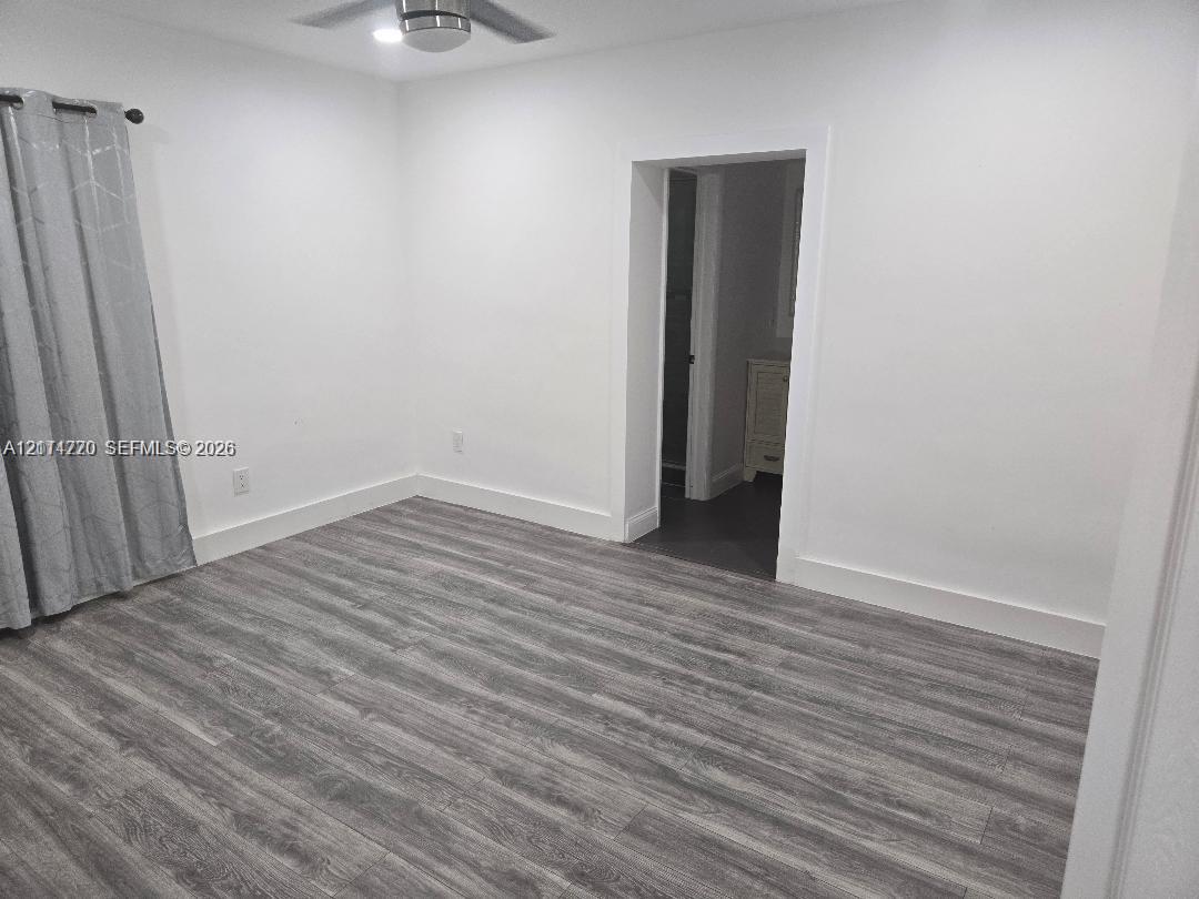 Interior space featuring wood-finish flooring, white walls, and a ceiling-mounted light fixture Interior space featuring wood-finish flooring, white walls, and a ceiling-mounted light fixture