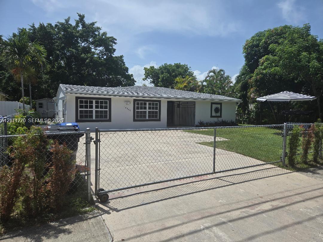 Single-story exterior featuring white stucco siding, a concrete driveway, a sliding chain-link entry gate, and a hip roof Single-story exterior featuring white stucco siding, a concrete driveway, a sliding chain-link entry gate, and a hip roof